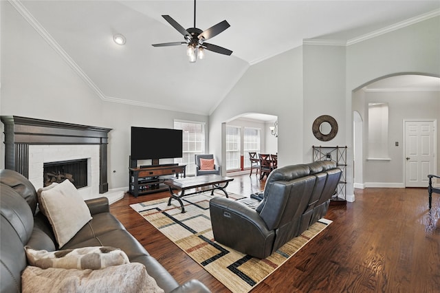 living room featuring arched walkways, a ceiling fan, baseboards, ornamental molding, and wood finished floors