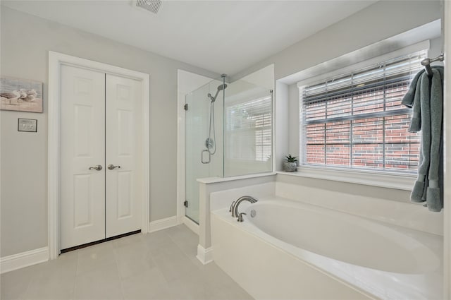 bathroom with a bath, a shower stall, tile patterned floors, and baseboards