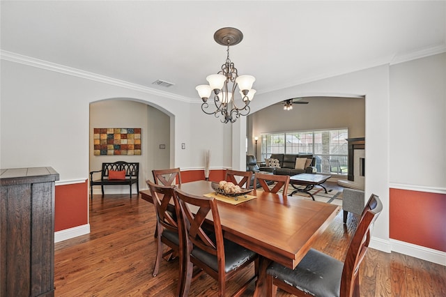 dining space with arched walkways, a chandelier, ornamental molding, wood finished floors, and baseboards