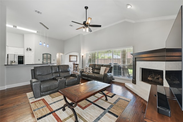 living area with ornamental molding, arched walkways, wood finished floors, high vaulted ceiling, and a ceiling fan