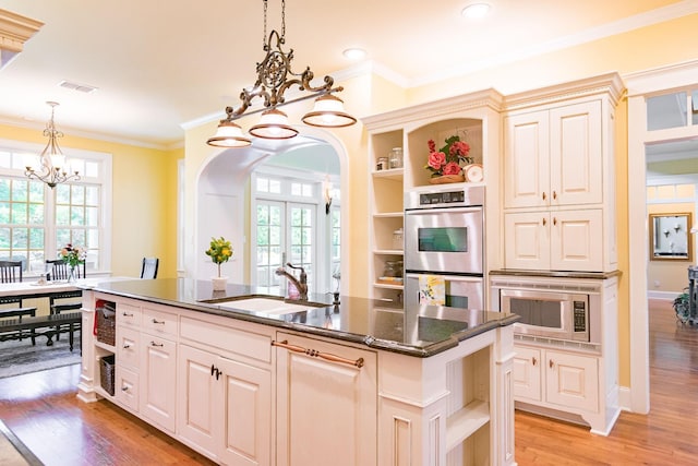 kitchen with open shelves, a sink, a chandelier, arched walkways, and appliances with stainless steel finishes