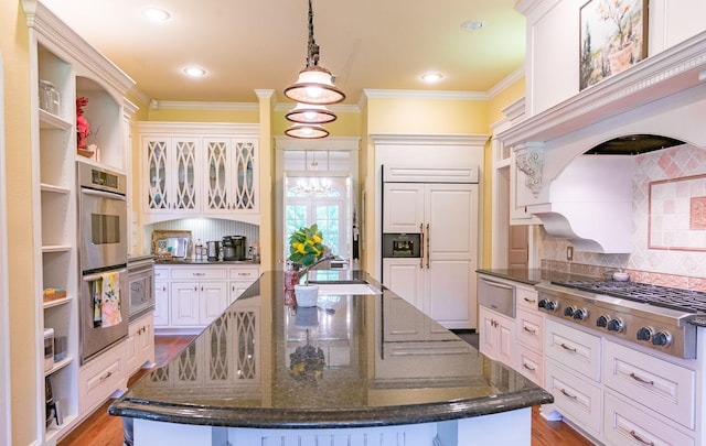 kitchen featuring appliances with stainless steel finishes, ornamental molding, a large island, decorative backsplash, and white cabinets