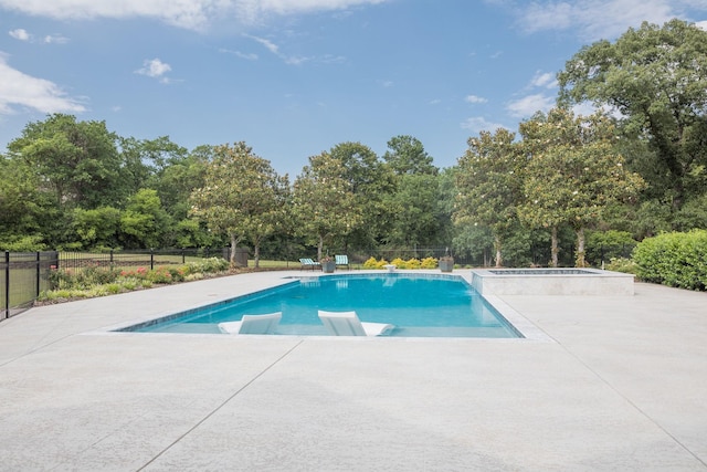 view of pool featuring an in-ground hot tub, a patio, view of wooded area, and fence