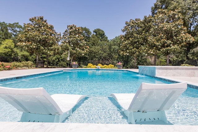 view of pool featuring view of wooded area