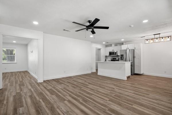 2309 Ruby Rd, Irving, TX 75060 - unfurnished living room with wood finished floors, baseboards, recessed lighting, ceiling fan, and a sink