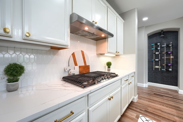 4533 Cheetah Trl, Frisco, TX 75034 - kitchen with under cabinet range hood, stainless steel gas cooktop, light wood-style floors, white cabinets, and decorative backsplash