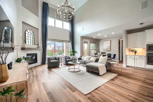 4533 Cheetah Trl, Frisco, TX 75034 - living room featuring a high ceiling, light wood-style floors, a fireplace, a chandelier, and recessed lighting