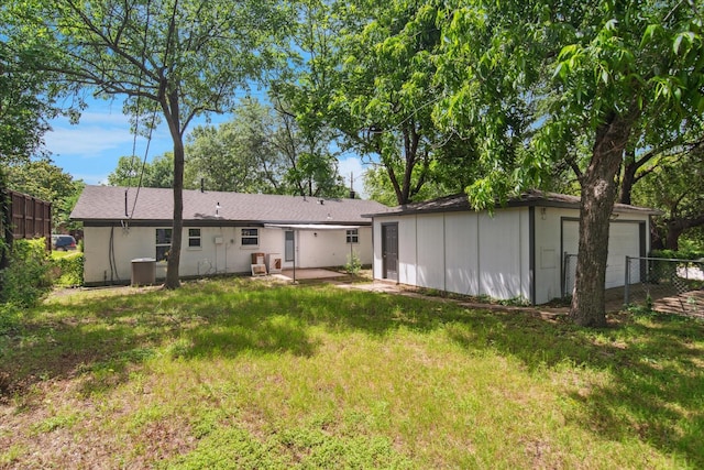 back of house with an outdoor structure, a detached garage, board and batten siding, central AC unit, and a patio