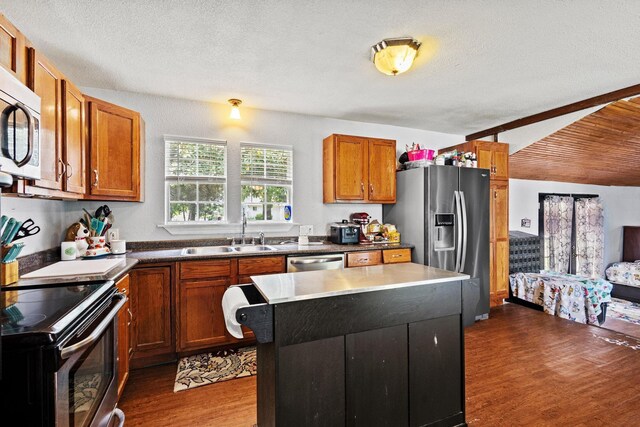 1801 Beavers Pt, Bonham, TX 75418 - kitchen with stainless steel appliances, a sink, dark wood-style flooring, brown cabinets, and a center island