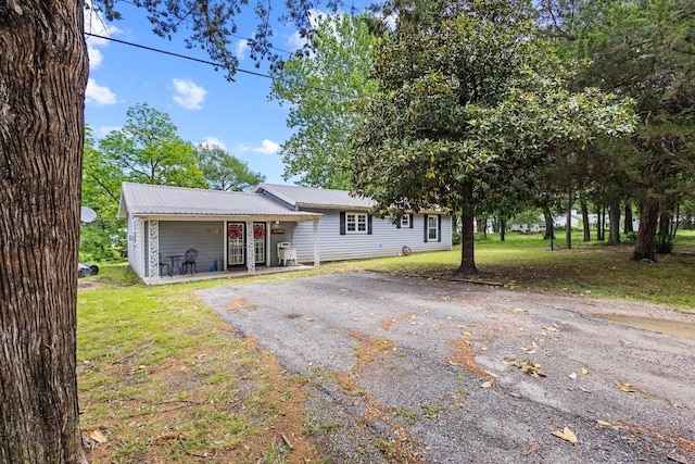 1801 Beavers Pt, Bonham, TX 75418 - view of front of house with a porch, asphalt driveway, metal roof, and a front lawn