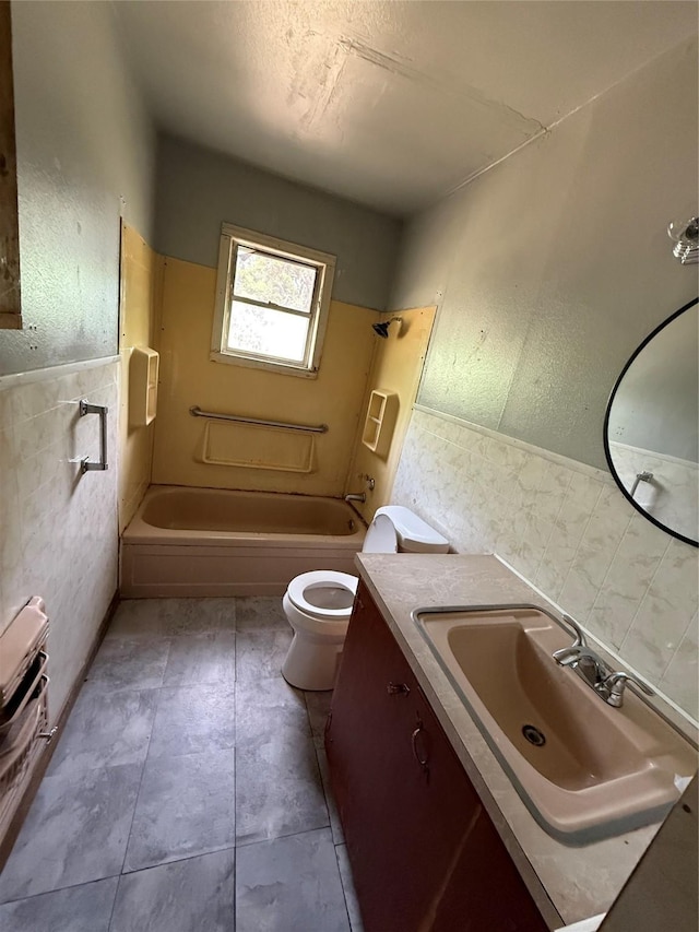 701 Perry, Santa Anna, TX 76878 - bathroom featuring toilet, tile walls, vanity,  shower combination, and wainscoting