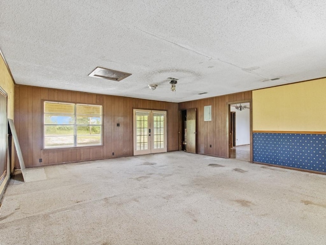 110 Twin Cir, Wortham, TX 76693 - carpeted spare room with french doors, wood walls, and a textured ceiling