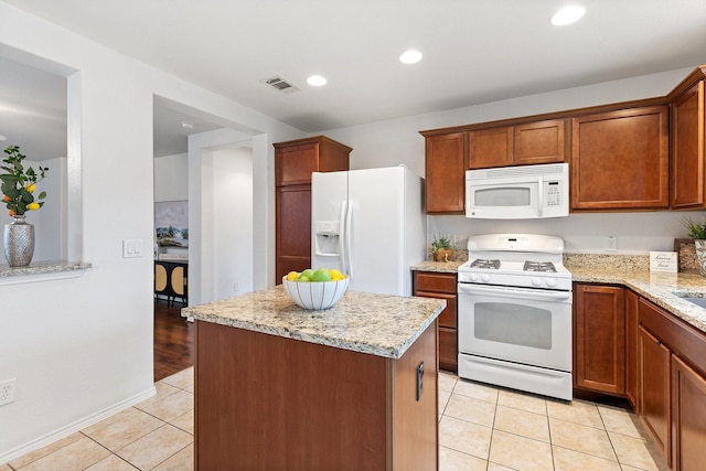 7735 Whirlwind Dr, Frisco, TX 75036 - kitchen featuring white appliances, a center island, light tile patterned flooring, light stone countertops, and recessed lighting