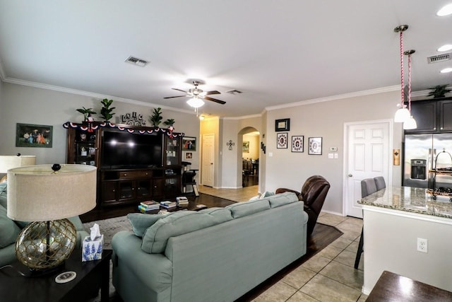 5516 Tama Dr, Waco, TX 76708 - living room with arched walkways, crown molding, ceiling fan, light tile patterned flooring, and baseboards