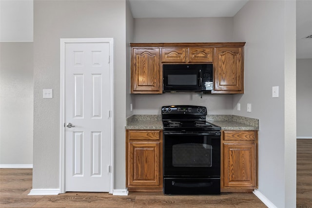 1502 Jacksons Run, Greenville, TX 75402 - kitchen featuring black appliances, wood finished floors, and baseboards