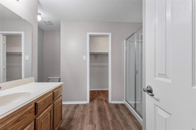 1502 Jacksons Run, Greenville, TX 75402 - bathroom with a stall shower, wood finished floors, vanity, and a spacious closet