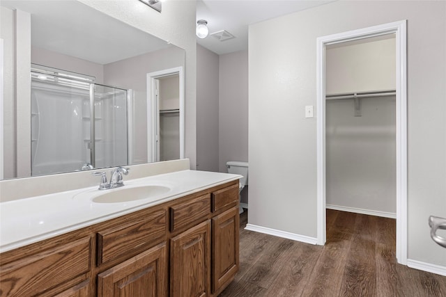 1502 Jacksons Run, Greenville, TX 75402 - bathroom featuring a shower stall, wood finished floors, a spacious closet, vanity, and baseboards