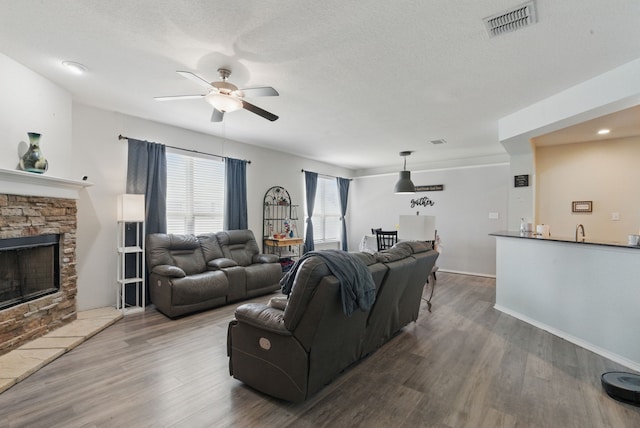 10957 Colonial Heights Ln, Fort Worth, TX 76179 - living room with ceiling fan, wood finished floors, a fireplace, and a textured ceiling