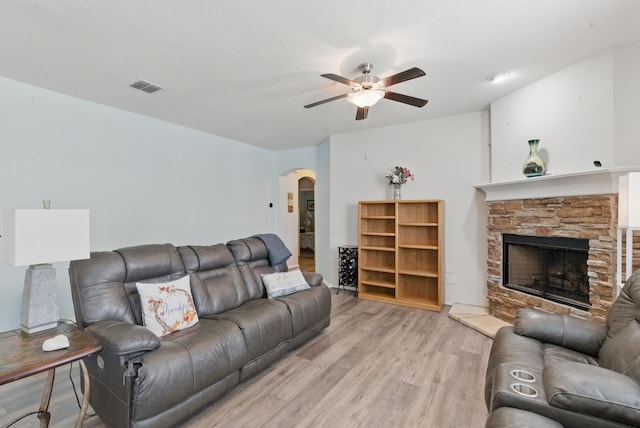 10957 Colonial Heights Ln, Fort Worth, TX 76179 - living room with arched walkways, a ceiling fan, light wood-style flooring, and a stone fireplace
