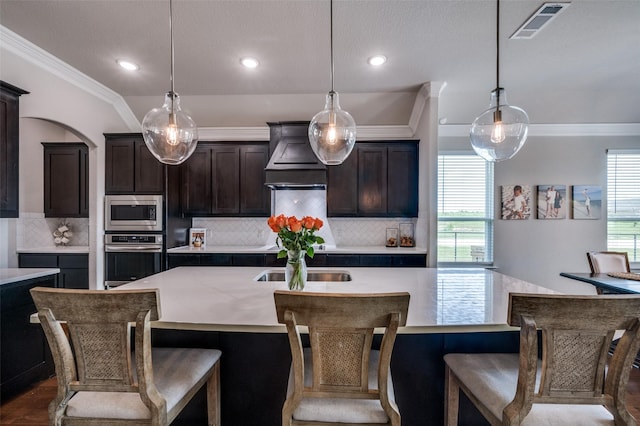 13400 Summer Moon Trl, Ponder, TX 76259 - kitchen with appliances with stainless steel finishes, crown molding, custom range hood, decorative backsplash, and a center island with sink