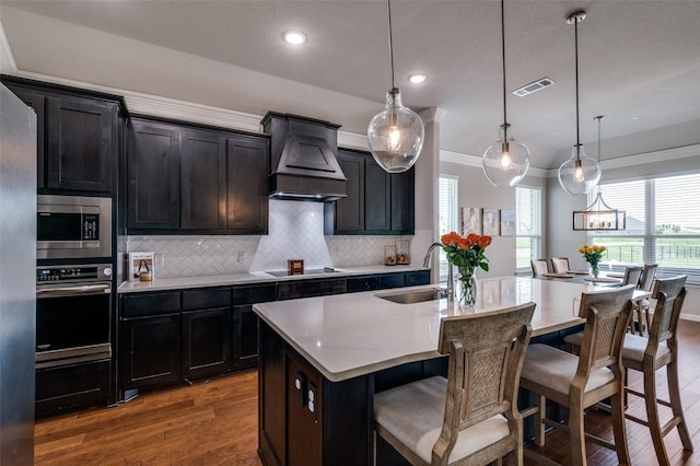 13400 Summer Moon Trl, Ponder, TX 76259 - kitchen with a sink, appliances with stainless steel finishes, custom range hood, wood finished floors, and a center island with sink