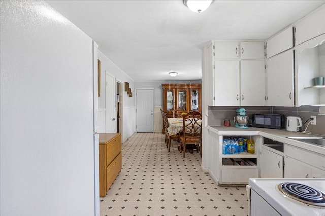 116 S Barron St, Arp, TX 75750 - kitchen featuring black microwave, light flooring, white cabinets, light countertops, and white range with electric cooktop