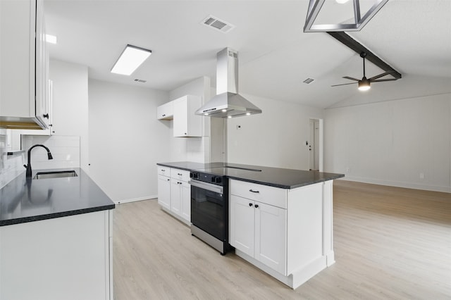 kitchen with island exhaust hood, a sink, oven, light wood-style floors, and dark countertops