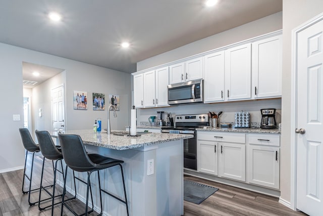 2358 Aylesbury Dr, Copperas Cove, TX 76522 - kitchen with appliances with stainless steel finishes, an island with sink, dark wood finished floors, white cabinetry, and recessed lighting