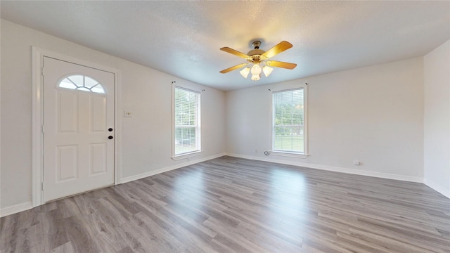 1107 Vine St, Weatherford, TX 76086 - foyer entrance featuring light wood finished floors, baseboards, a ceiling fan, and a textured ceiling