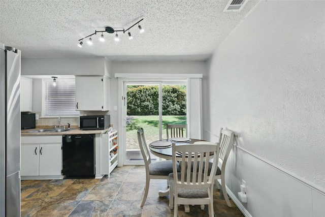 2433 Loyce Dr, Mesquite, TX 75149 - kitchen with black appliances, a textured ceiling, white cabinetry, stone finish floors, and a sink