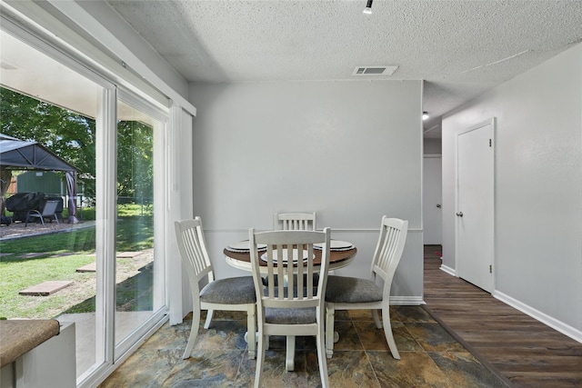 2433 Loyce Dr, Mesquite, TX 75149 - dining space featuring a textured ceiling, baseboards, and wood finished floors
