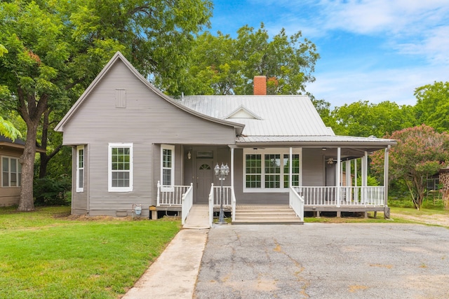 1315 E Pecan St, Gainesville, TX 76240 - view of front of home with a chimney, covered porch, a front yard, and metal roof