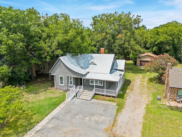 1315 E Pecan St, Gainesville, TX 76240 - view of front of home with covered porch, a chimney, a front yard, and metal roof