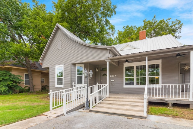 1315 E Pecan St, Gainesville, TX 76240 - view of front facade featuring a ceiling fan, a chimney, a front lawn, and metal roof