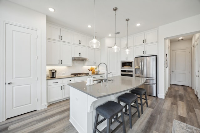 424 Somerville Dr, Mckinney, TX 75071 - kitchen featuring appliances with stainless steel finishes, a sink, a kitchen bar, white cabinets, and decorative backsplash