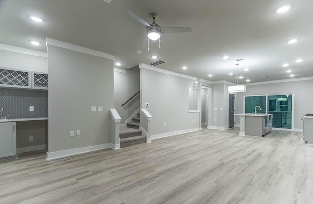 3325 Norris St, Plano, TX 75074 - unfurnished living room featuring a ceiling fan, ornamental molding, light wood finished floors, stairs, and wet bar