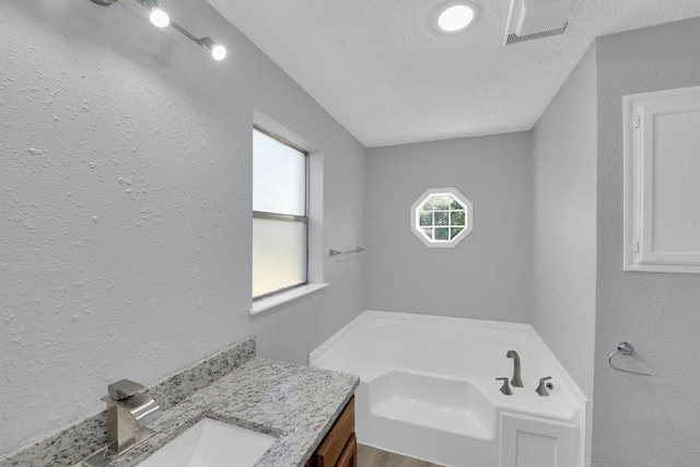 3355 La Mesa Dr, Weatherford, TX 76085 - full bathroom featuring a garden tub, a textured ceiling, vanity, and a textured wall