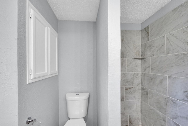 3355 La Mesa Dr, Weatherford, TX 76085 - bathroom featuring a textured ceiling, toilet, and tiled shower