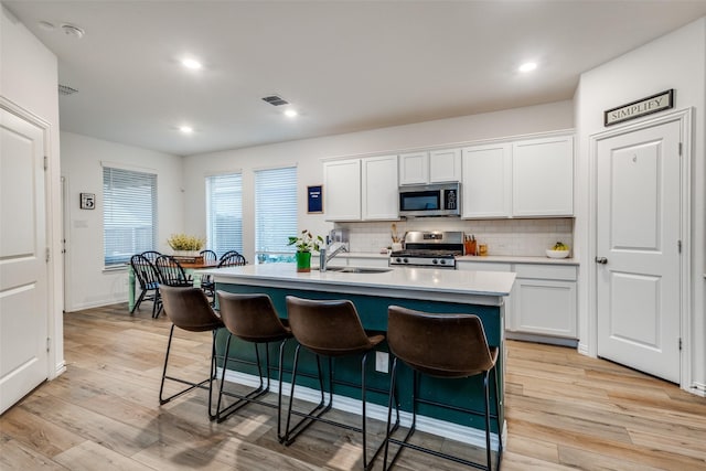 1252 Milfoil Dr, Justin, TX 76247 - kitchen with appliances with stainless steel finishes, a sink, a kitchen breakfast bar, backsplash, and white cabinetry