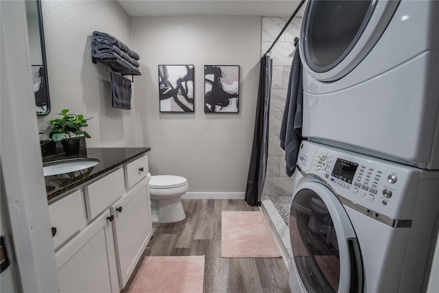 1701 W College St, Sherman, TX 75092 - bathroom with stacked washer / dryer, toilet, wood finished floors, a stall shower, and vanity