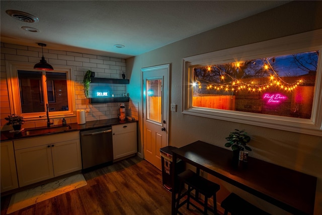 1701 W College St, Sherman, TX 75092 - kitchen with stainless steel dishwasher, a sink, dark countertops, dark wood-style floors, and backsplash