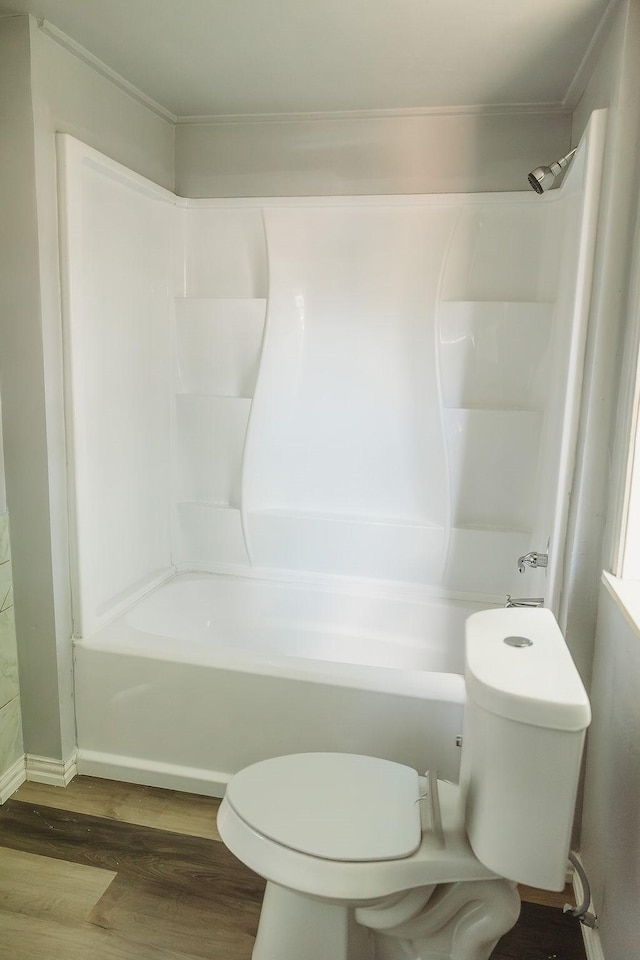 bathroom featuring wood finished floors, toilet, washtub / shower combination, and crown molding