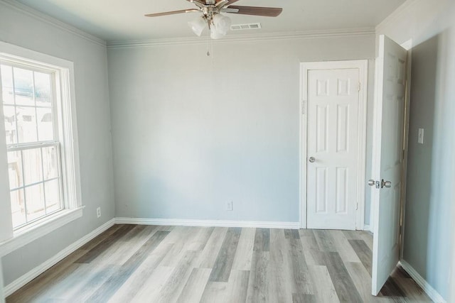 unfurnished room featuring ceiling fan, plenty of natural light, light wood-type flooring, and crown molding