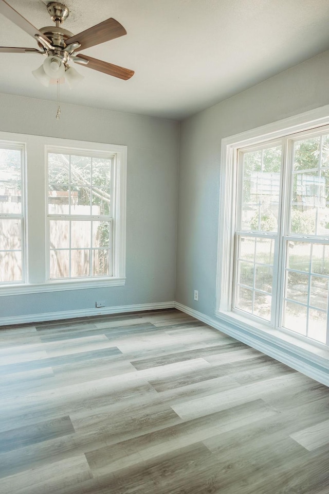 empty room with baseboards, ceiling fan, and wood finished floors