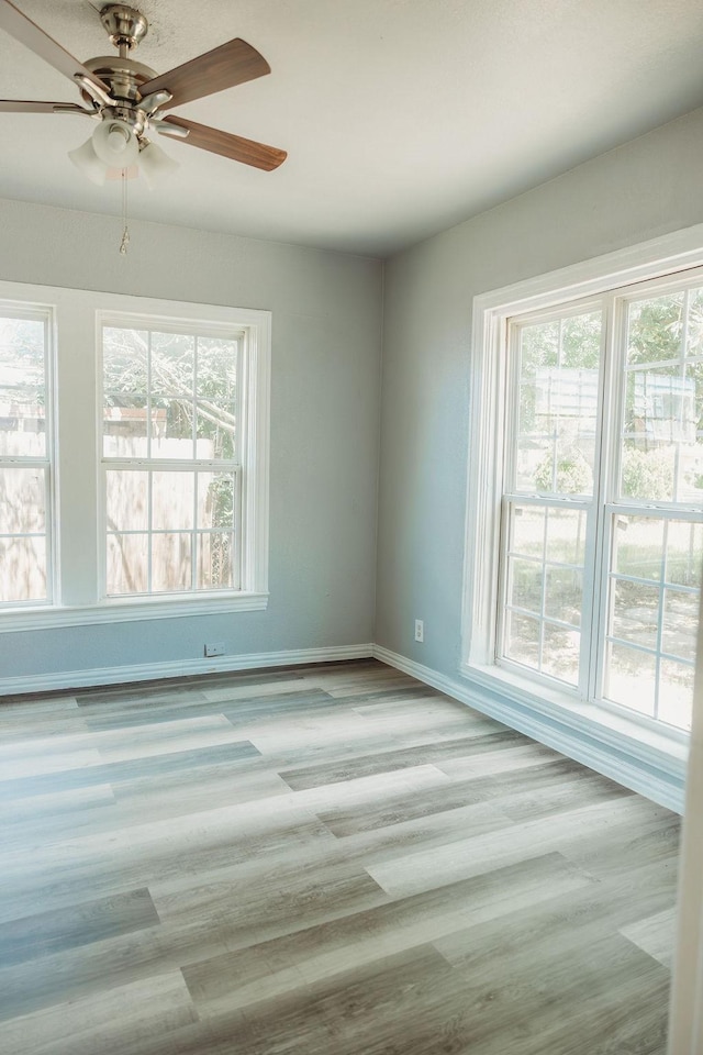 unfurnished room with baseboards, ceiling fan, and wood finished floors