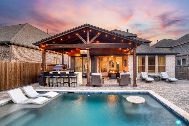 6108 Lipan Ln, Mckinney, TX 75070 - pool at dusk featuring exterior kitchen, a fenced backyard, a patio area, and an outdoor living space