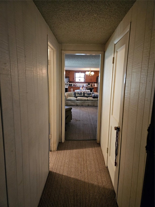 193 County Road 1704, Clifton, TX 76634 - hallway featuring a chandelier, carpet floors, a textured ceiling, and wood walls