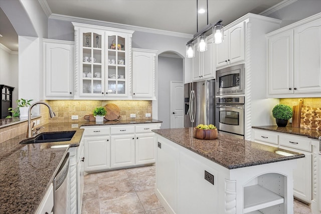 8001 Sutherland Ln, Plano, TX 75025 - kitchen with stainless steel appliances, a sink, arched walkways, ornamental molding, and glass insert cabinets