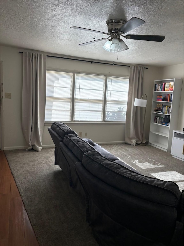 living room featuring a textured ceiling, a ceiling fan, carpet flooring, and baseboards