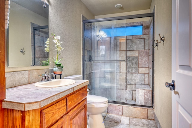 2514 Colquitt Rd, Terrell, TX 75160 - full bathroom featuring a textured wall, a shower stall, toilet, vanity, and stone finish flooring